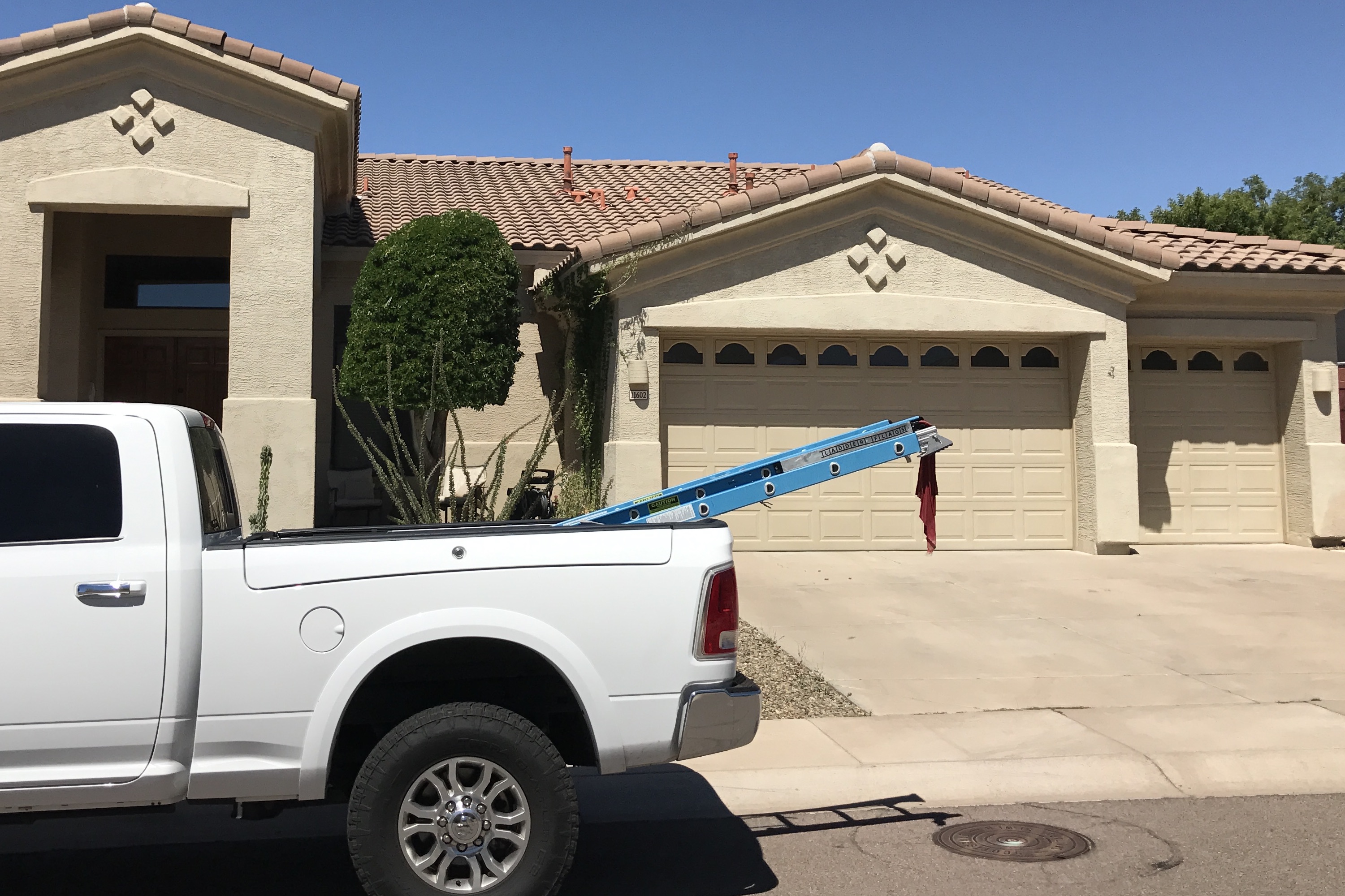 Professional and 'OSHA' Compliant Ladder Flag displayed on ladder in truck box parked in front of new tile roof on home an